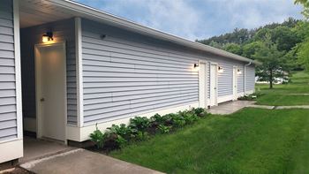 a view of the side of a white house with white siding and a garden